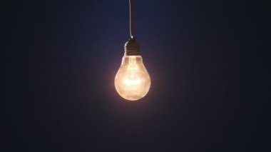 Klasik lamba koyu mavi arka planda parlıyor ve yanıp sönüyor. Edison ampulü yavaşça açılıp kapanıyordu. Yakından yanıp sönüyordu. Ilık yanıp sönen filament. Vintage Incandescent ampulü. Fikir, kopyalama alanı. 4K