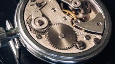 Timelapse of mechanism of vintage stopwatch with rotation close-up. Round clock watch mechanism working, macro. Old retro clockwork gears, cogwheels, and pendulum movement inside the ancient clock. 4K