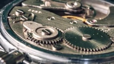 Timelapse of vintage stopwatch mechanism close-up. Round clock watch mechanism working in a macro. Old retro clockwork gears, cogwheels, and pendulum movement inside the rotation ancient stopwatch.