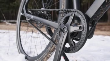Belt drive on a bicycle standing on the snow in a winter forest. A close-up of a modern belt drive instead of a chain is great working with a planetary hub. Toothed belt, gear change mechanism. 4K