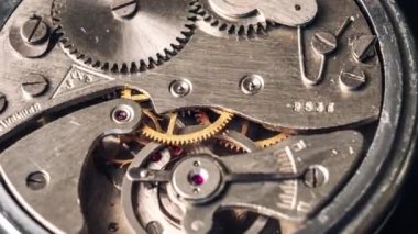Timelapse of vintage stopwatch mechanism close-up. Round clock watch mechanism working in a macro. Old retro clockwork gears, cogwheels, and pendulum movement inside the rotation ancient stopwatch.