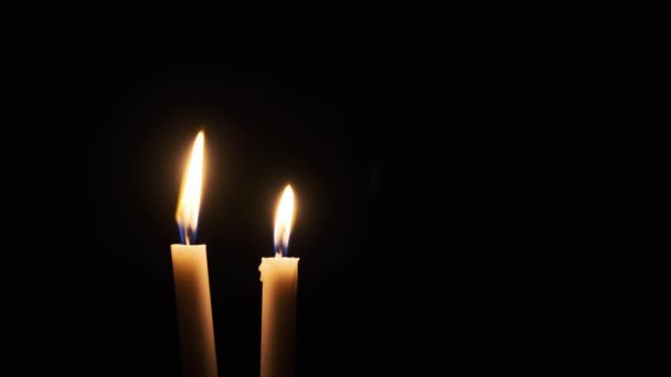 两支蜡烛在黑色的背景上点燃 黄色闪烁的火焰照亮了黑暗 夜间燃烧着的温暖的火光 随风飘荡 孤立无援 科皮斯4K — 图库视频影像