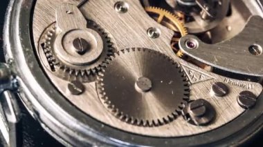 Timelapse of vintage stopwatch mechanism close-up. Round clock watch mechanism working in a macro. Old retro clockwork gears, cogwheels, and pendulum movement inside the rotation ancient stopwatch.