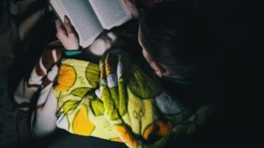 Baygınlık sırasında fener ışığında kitap okuyan bir kadın. Rahat bir odada, kanepede uzanmış sabahlık giymiş bir kadın geceleri kitap okumakla meşgul. Oturma odasındaki kitabın tadını çıkarıyorum..