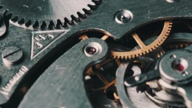Mechanism of vintage stopwatch close-up. Round clock watch mechanism working in macro. Old retro clockwork gears, cogwheels, and pendulum movement inside the ancient stopwatch.