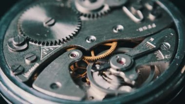 Mechanism of vintage stopwatch close-up. Round clock watch mechanism working in macro. Old retro clockwork gears, cogwheels, and pendulum movement inside the ancient stopwatch.