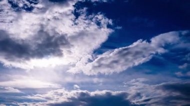 Timelapse of cumulus storm clouds moving in the sky with sun over the horizon. Cloud space background with dark, light and grey clouds changing shape, time lapse. Change of weather. Nature, copy space