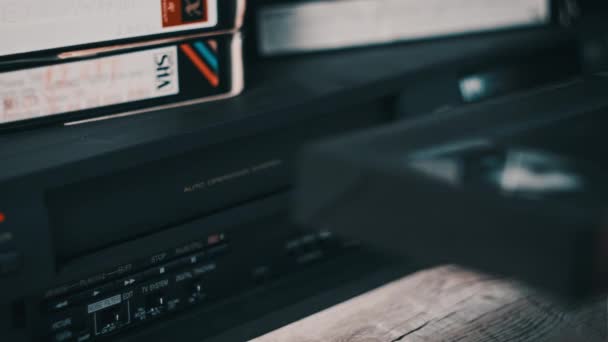 男性手将Vhs盒式磁带插入录像机 桌上放有许多盒式磁带的黑色老式盒式磁带录音机 将复古Vhs磁带插入到老式播放器中 家庭录像档案 — 图库视频影像