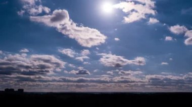 Cumulus clouds moving in the sky with sun over the horizon, timelapse. Cloud space background with dark and light clouds changing shape, time lapse. Change of weather. Nature, sky clouds, copy space