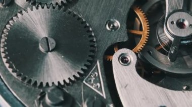 Clock mechanism rotates close-up. The working mechanism of round stopwatch spinning in macro. Detailed view of old retro clockwork gears, cogwheels and pendulum movement inside the ancient metal watch