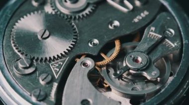 Clock mechanism rotates close-up. Vintage round stopwatch mechanism working in a macro. Old retro clockwork gears, cogwheels, and pendulum movement inside the ancient metal watch.
