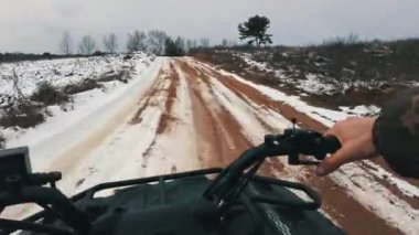 Karlı arazide dört tekerli bisiklete binen bir adamın direksiyon manzarası. POV kışın karla kaplı bir yolda ATV 'yi kontrol ediyor. Karlı bir alanda dört tekerlekli bir arabaya binmek. Meslek, off-road yarışı