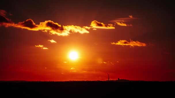 地平線上のオレンジ色の空に沈む夕日 太陽の光が降り注ぐ大きな赤い太陽 素晴らしい壮大な雲の空間 鮮やかな色 タイムラプス 黄色の空の日没 — ストック動画