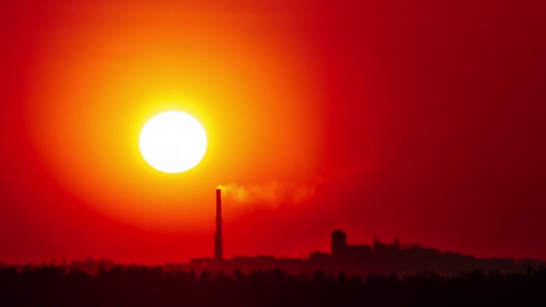 煙管で工場の上空のオレンジ色の空の日没の経過 大きな明るい赤い太陽が地平線の上を動きます 素晴らしい壮大な雲の空間 鮮やかな色 タイムラプス 晴れた空に沈む夕日 — ストック動画