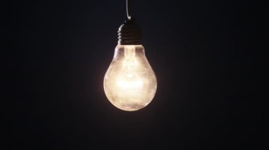 Siyah arka planda parlak ve yanıp sönen bir lamba. Edison ampulü yavaşça açılıp kapanıyordu. Yakından yanıp sönüyordu. Ilık yanıp sönen filament. Retro klasik ampul. Uzaklaştır
