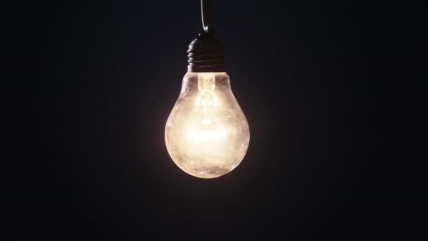 白熱灯が黒を背景に輝き ちらつきます エジソン電球がゆっくりとオンとオフになり ライトが閉まりました 暖かい点滅フィラメント レトロな古典的な電球 ズームアウト — ストック動画
