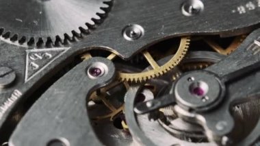 Mechanism of vintage stopwatch close-up. Round clock watch mechanism working in macro. Old retro clockwork gears, cogwheels, and pendulum movement inside the ancient stopwatch.