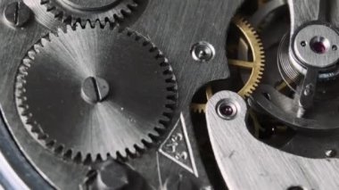 Clock mechanism rotates close-up. The working mechanism of round stopwatch spinning in macro. Detailed view of old retro clockwork gears, cogwheels and pendulum movement inside the ancient metal watch