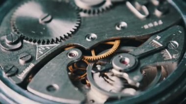 Mechanism of vintage stopwatch close-up. Round clock watch mechanism working in macro. Old retro clockwork gears, cogwheels, and pendulum movement inside the ancient stopwatch.