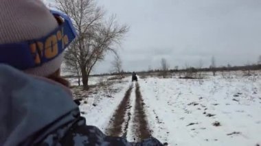 First-person view of a woman riding on a quad bike in winter. ATV bike ride through the snowy landscape. Ride a 4x4 ATV on a winter snow-covered path in a snowy area. Winter vacation. Off-road racing.