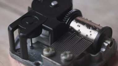 Old music box mechanism with spinning cylinder and cogs in macro. Retro music box clockwork device with rotating drum with projections touching the records creates music. Toy barrel organ rotates. 4K