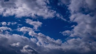 Timelapse of cumulus clouds moving in the blue sky. Cloud space background with dark, light and grey clouds changing shape, time lapse. Change of weather. Nature, sky clouds, copy space