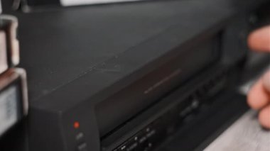 Video oynatıcıdan VHS kaseti çıkar. Erkek el, birçok arşivlenmiş video kaset içeren eski bir video kayıt cihazından VHS çekiyor. VHS retro oynatıcı. Ev videosu kavramı, eski teknoloji