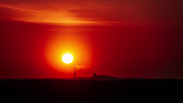 夕阳西下的时间 在工厂上方的橙色天空中 烟斗烟消云散 大而明亮的红色太阳从地平线上升起 华丽的史诗般的云彩空间 生气勃勃的色彩 时间流逝 晴空万里的日落 — 图库视频影像