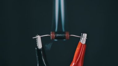 The resistor heats up with smoke under a high electric current, short circuit. Resistor - An electrical component burns out when exposed to high voltage. Close-up, resistance. Current strength, power