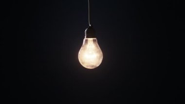 Yanan lamba yanıyor ve arka planda yanıp sönüyor. Klasik ampul yavaşça açılıp kapanıyordu. Ilık yanıp sönen filament. Tungsten ampulü, klasik ışığın rahat parlaklığı. Fikir, boşluk 4K 'yi kopyala