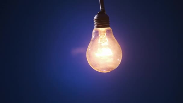 Žárovka Drátě Pohupuje Strany Stranu Rozsvítí Blikajícími Světélky Tmavomodrém Pozadí — Stock video
