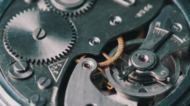 Clock mechanism rotates close-up. Vintage round stopwatch mechanism working in a macro. Old retro clockwork gears, cogwheels, and pendulum movement inside the ancient metal watch.