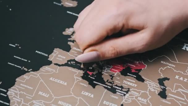 女性の手スクラッチ世界地図の表面にイタリアの国をスクラッチ ヨーロッパ諸国とのスクラッチ世界地図 クローズアップ スクラッチは 旅行地図上の国を訪問した スクラッチマップ上の国を消去 — ストック動画