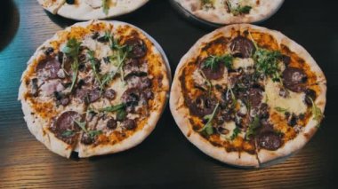 Pizzacıda bir sürü pizza var, yakın plan. Lokantada et, domuz pastırması, sucuk, peynir vb. ile iştah açıcı İtalyan pizzasından bol bol var. Çeşitli pizza çeşitleri. 4K