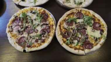 Pizzacıda bir sürü pizza var, yakın plan. Lokantada et, domuz pastırması, sucuk, peynir vb. ile iştah açıcı İtalyan pizzasından bol bol var. Çeşitli pizza çeşitleri. 4K