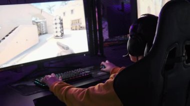 Genç oyuncu profesyonel bir oyun koltuğunda oturur ve E-spor kulübünde video oyunları oynar. Kulaklıklı bir çocuk bilgisayar kulübünde neon ışıkları olan bir video oyununa odaklanıyor. Oyun kulübünde genç, hobi olarak.
