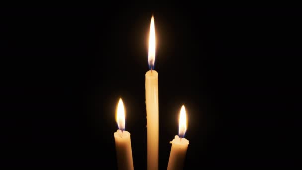 三支蜡烛在黑色的背景上燃烧 孤立的黄色闪烁着的火焰的特写照亮了黑暗 科皮尼斯 烛焰的温暖之火随风飘扬 文字的位置 — 图库视频影像