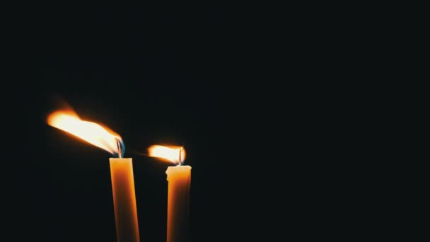 两支蜡烛在黑色的背景上燃烧 黄色闪烁的火焰的特写照亮了黑暗 孤立无援 科皮斯温暖的火光在夜晚轻风中飘扬 — 图库视频影像