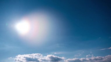 Mavi gökyüzünde, parlak güneşin altında hareket eden bulutlar, zaman kavramı. Bulutuzay arkaplanı. Muhteşem cennette hafif kabarık bulutların zamanı. Manzaralı atmosfer. Hava değişikliği. Doğa. 4K