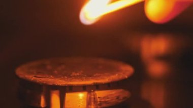 Ignite the gas on the stove with a matchstick in slow motion, close-up. Manual ignition of the gas burner in home kitchen. Burning blue flame of natural gas, macro. Burner operation, Fire on the stove