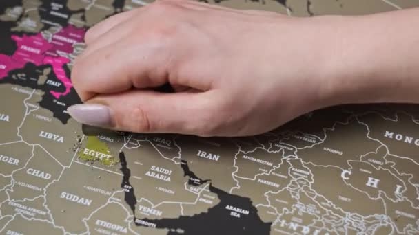女性の手は スクラッチ世界地図の表面にエジプトの国をスクラッチ 多くの国 クローズアップで世界地図をスクラッチ 旅行マップ上の訪問国を消去します 旅の計画の概念 — ストック動画