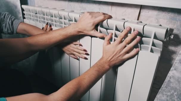手は放熱器によって暖められます 冷凍男性と女性の手は 家庭用バッテリーに触れ 暖かくしようとします 寒い季節の概念の間の家の温度および暖房家 アパートの寒さ — ストック動画
