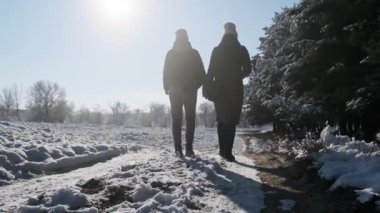 İki kız kış ormanında el ele yürüyorlar. Yavaş çekimde, dikiz aynasıyla. Parlak güneşe karşı kar yolunda yürüyen kadın kız arkadaşlar. Sevgi dolu bir çift adımın arka görüntüsü. LGBT, lezbiyen