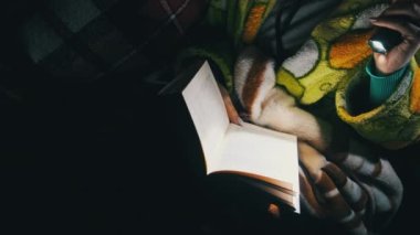 Baygınlık sırasında fener ışığında kitap okuyan bir kadın. Rahat bir odada, kanepede uzanmış sabahlık giymiş bir kadın geceleri kitap okumakla meşgul. Oturma odasındaki kitabın tadını çıkarıyorum..