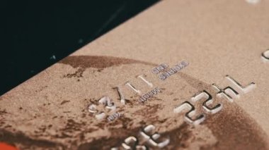 Altın bankamatik kartı yakın plan çekimde. Kredi kartında plastiğin numaraları var. Plastik banka kartı makroda dönüyor. Çevrimiçi ve perakende alışveriş için ödeme yöntemleri. Para, tasarruf, kredi kavramı