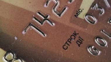 Plastik kredi kartı yakın plan çekiliyor. Plastik banka kartı makroda dönüyor. Çevrimiçi ödeme yöntemleri ve perakende alışveriş. Plastik üzerinde numaraları olan altın banka kartı. Para, tasarruf, kredi kavramı