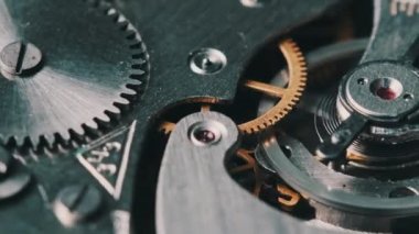 Clock mechanism rotates close-up. The working mechanism of round stopwatch spinning in macro. Detailed view of old retro clockwork gears, cogwheels and pendulum movement inside the ancient metal watch