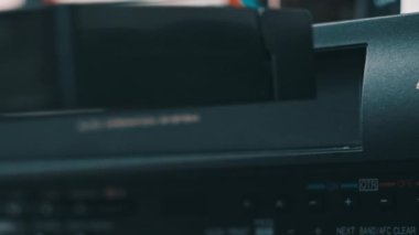Video oynatıcıya VHS kaset ekle. Masada bir sürü arşivlenmiş video kaset kaydedici var. Erkek el, eski VHS kaseti retro oynatıcıya sokuyor. Ev videosu, nostalji.