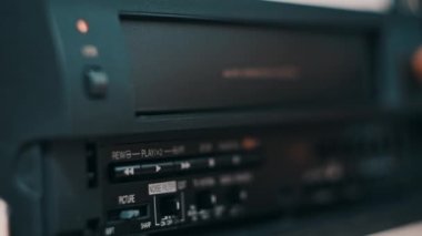 Video oynatıcıdan VHS kaseti çıkar. Erkek el bir düğmeye basar ve birçok arşivlenmiş video kasetle birlikte masadaki klasik video kayıt cihazından VHS 'yi çıkarır. VHS retro oynatıcı. Ev videosu, eski kaset