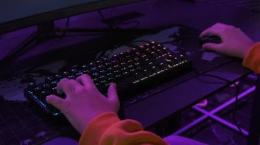 Modern Esport Kulübü 'nde gençler monitörün önünde oturur ve bir nişancı oyunu oynar. PC klavyesinde neon ışıkta duran bir çocuğun elleri görülüyor. Oyun kulübündeki gençler bilgisayar oyunları oynarlar. Sanal spor